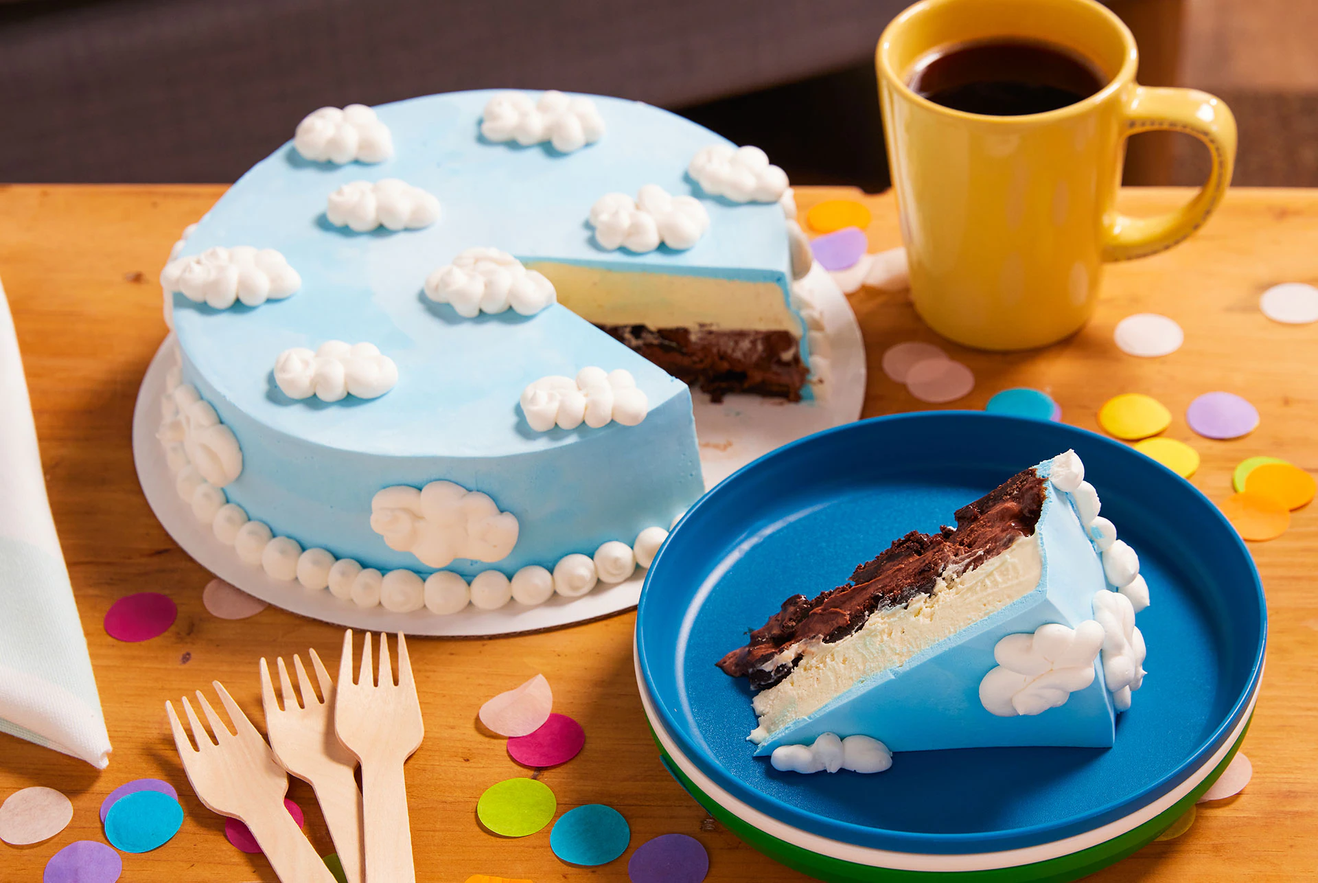 An ice cream cake with a slice from it on a plate next to a cup